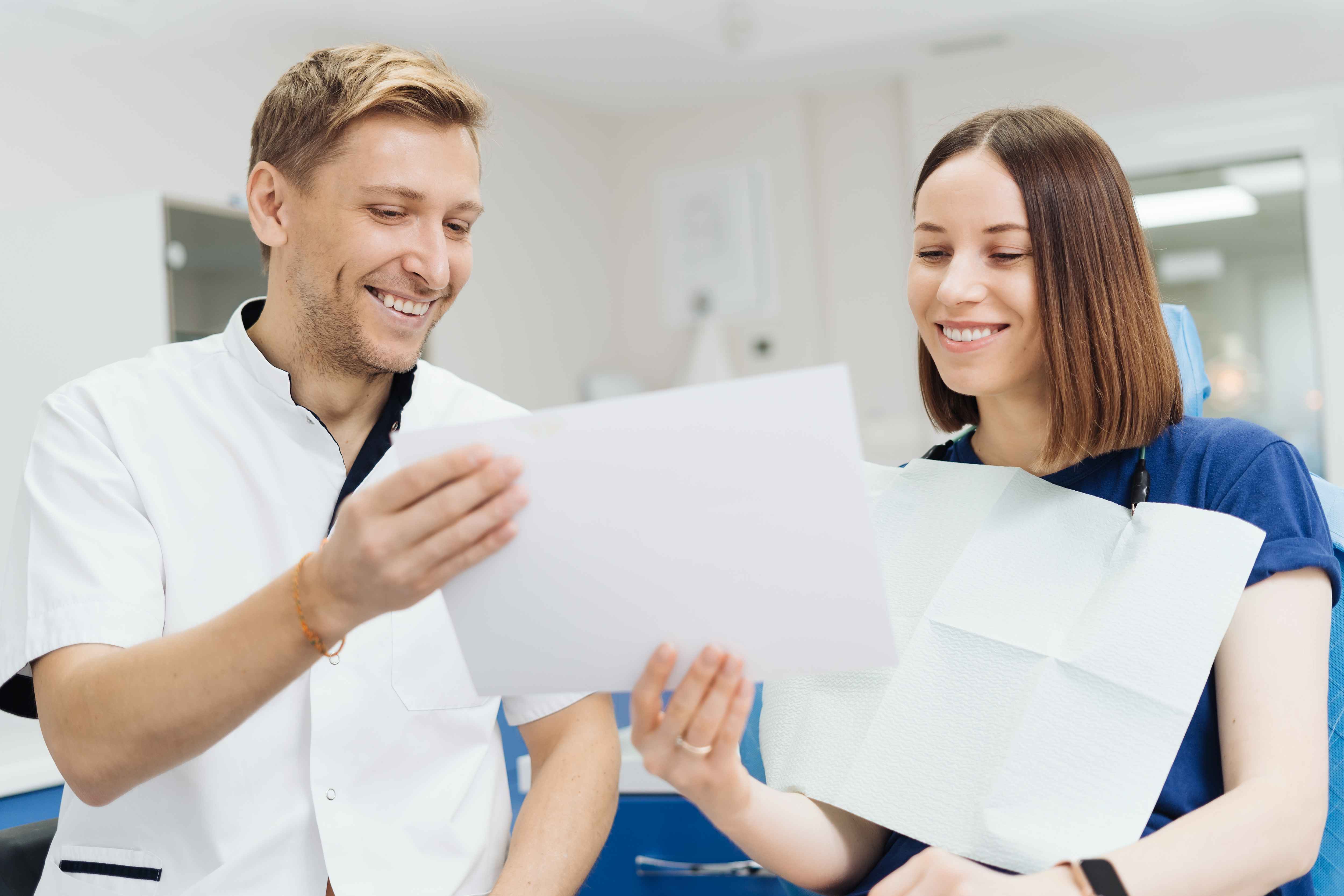A man with a magnifying glass examines a dental insurance policy